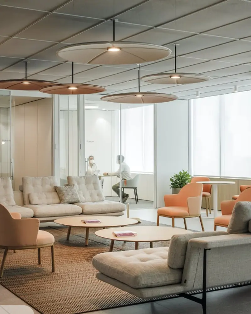 Office lounge with tufted sofas, blush accent chairs and disc pendant lighting